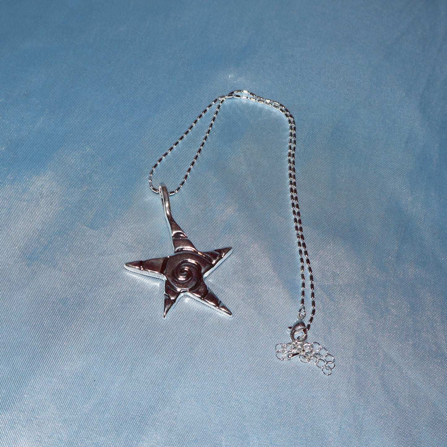 Star pendant, with a swirl design, silver chain necklace.