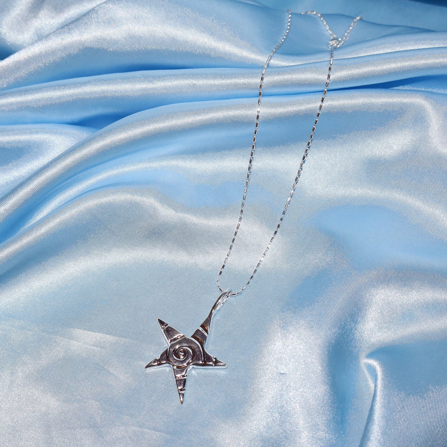 Star pendant, with a swirl design, silver chain necklace.