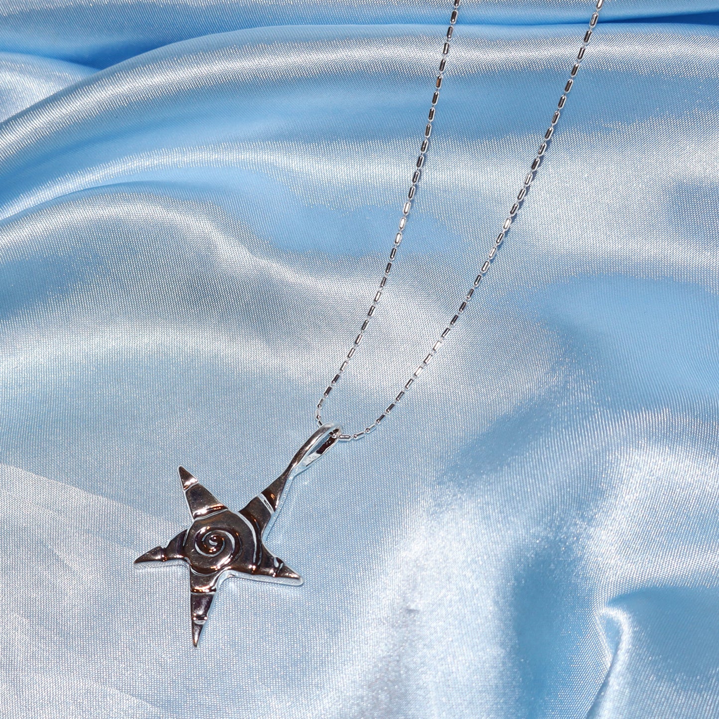 Star pendant, with a swirl design, silver chain necklace.