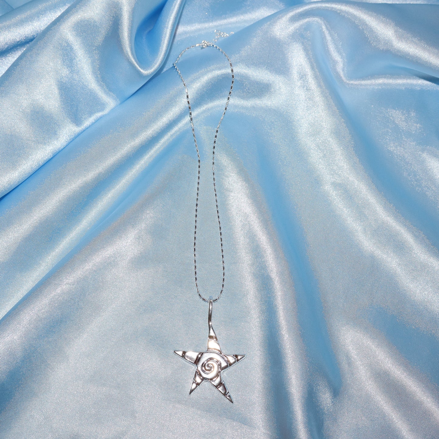 Star pendant, with a swirl design, silver chain necklace.