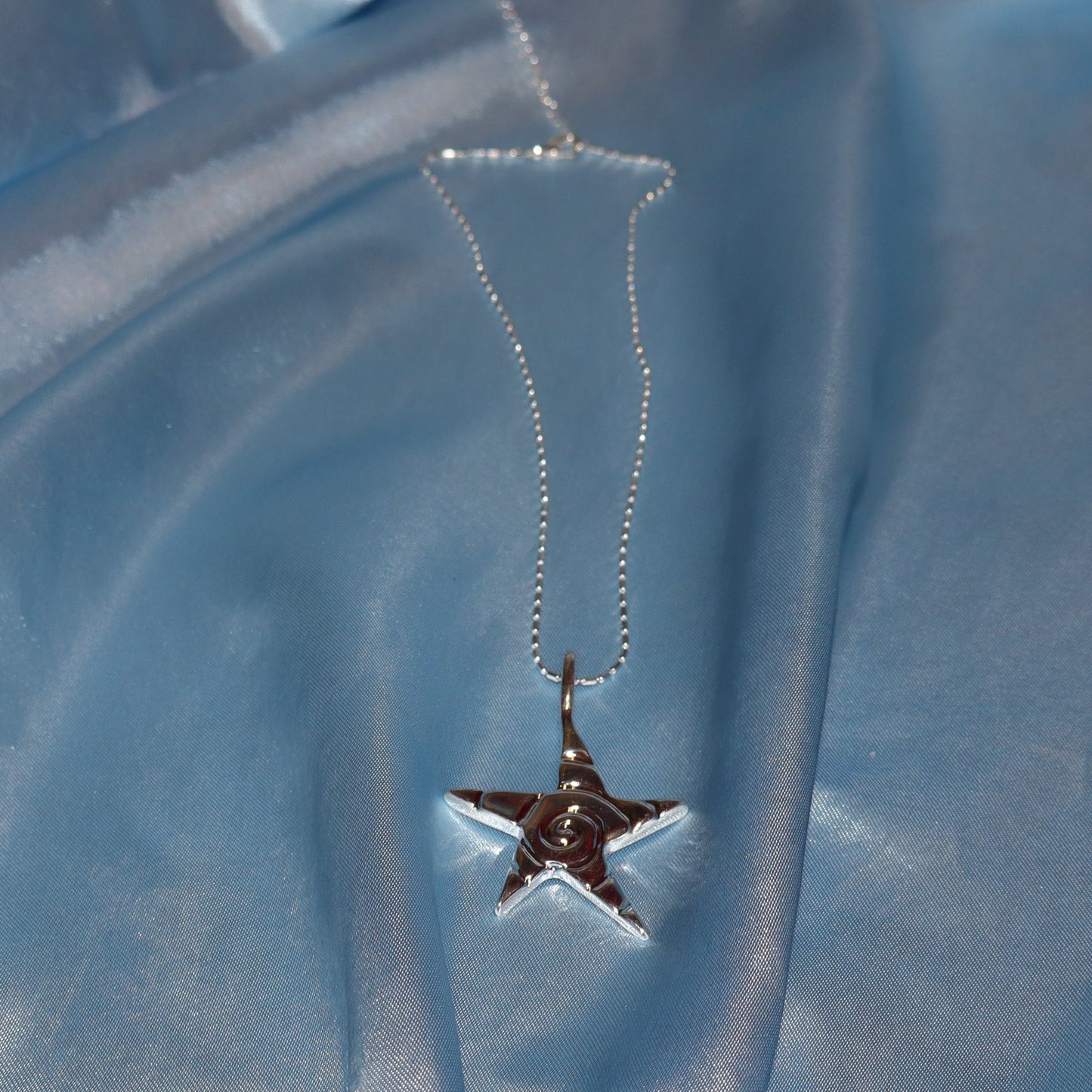 Star pendant, with a swirl design, silver chain necklace.