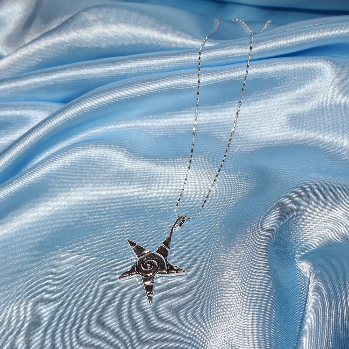 Star pendant, with a swirl design, silver chain necklace.