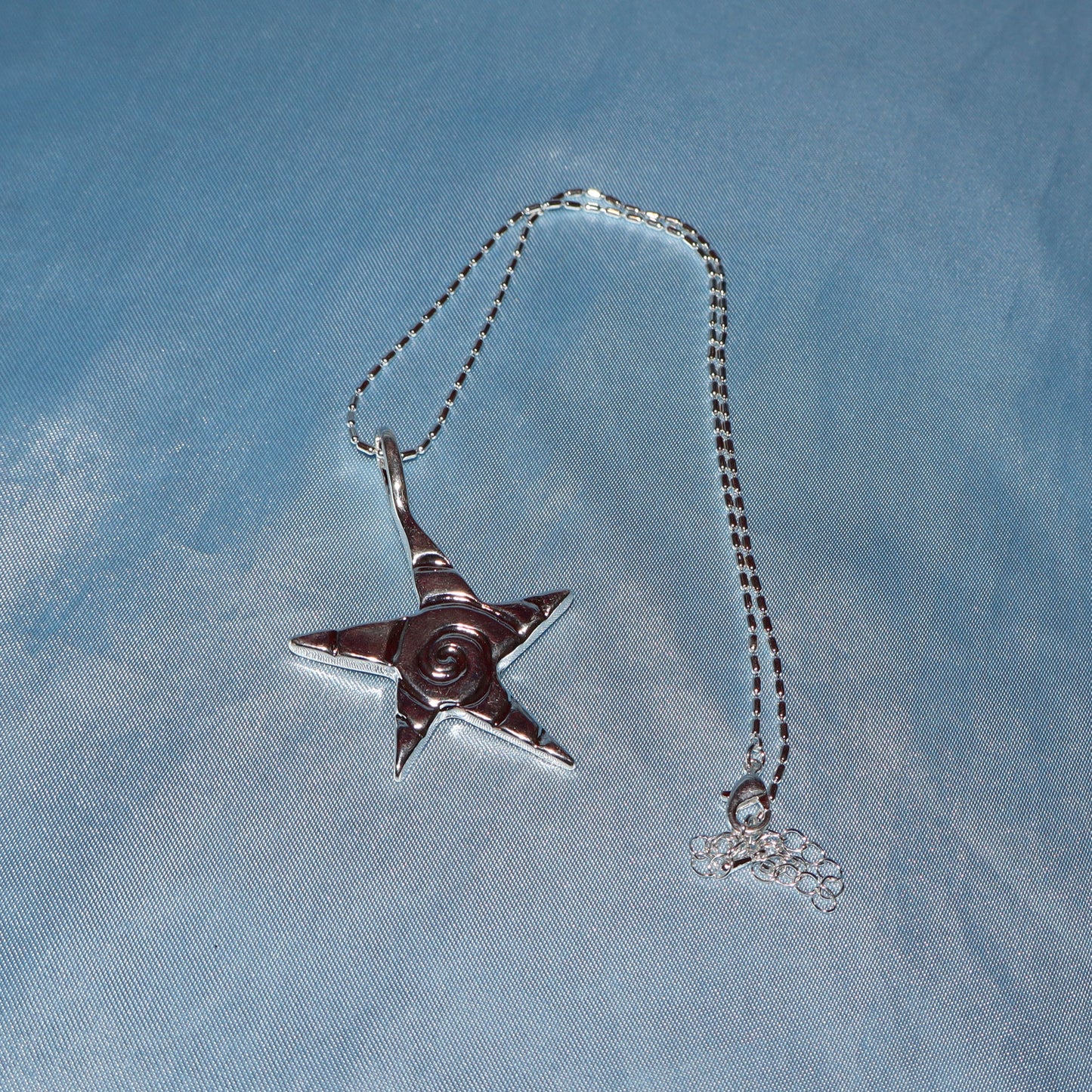 Star pendant, with a swirl design, silver chain necklace.