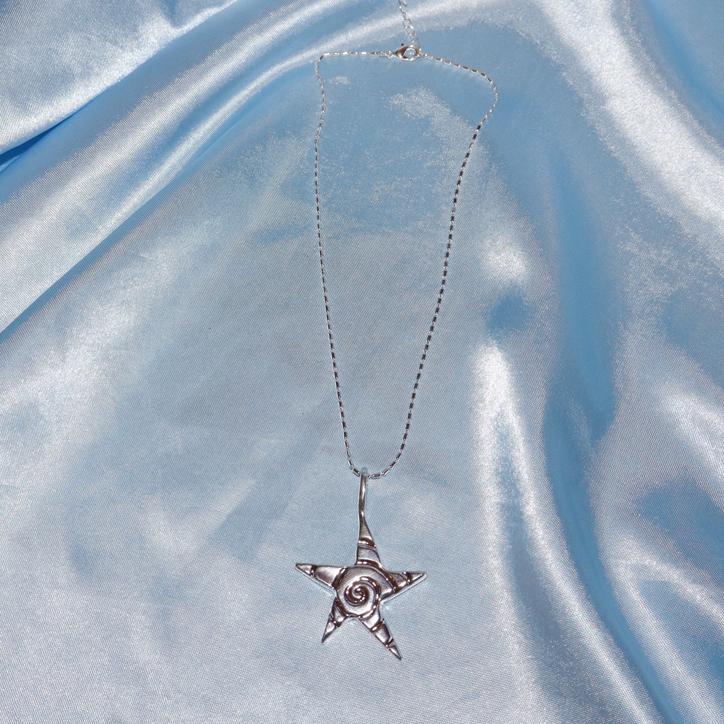 Star pendant, with a swirl design, silver chain necklace.
