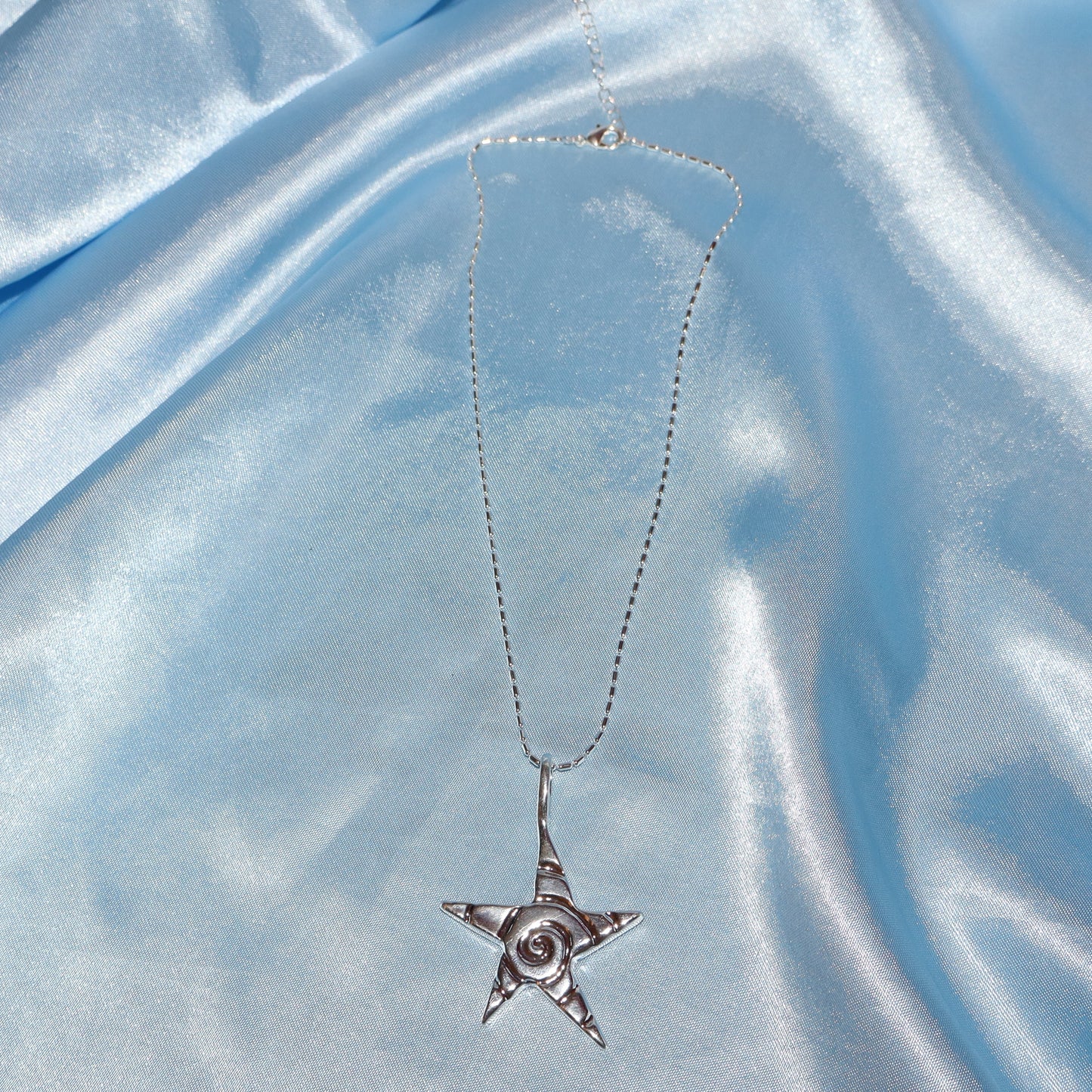 Star pendant, with a swirl design, silver chain necklace.