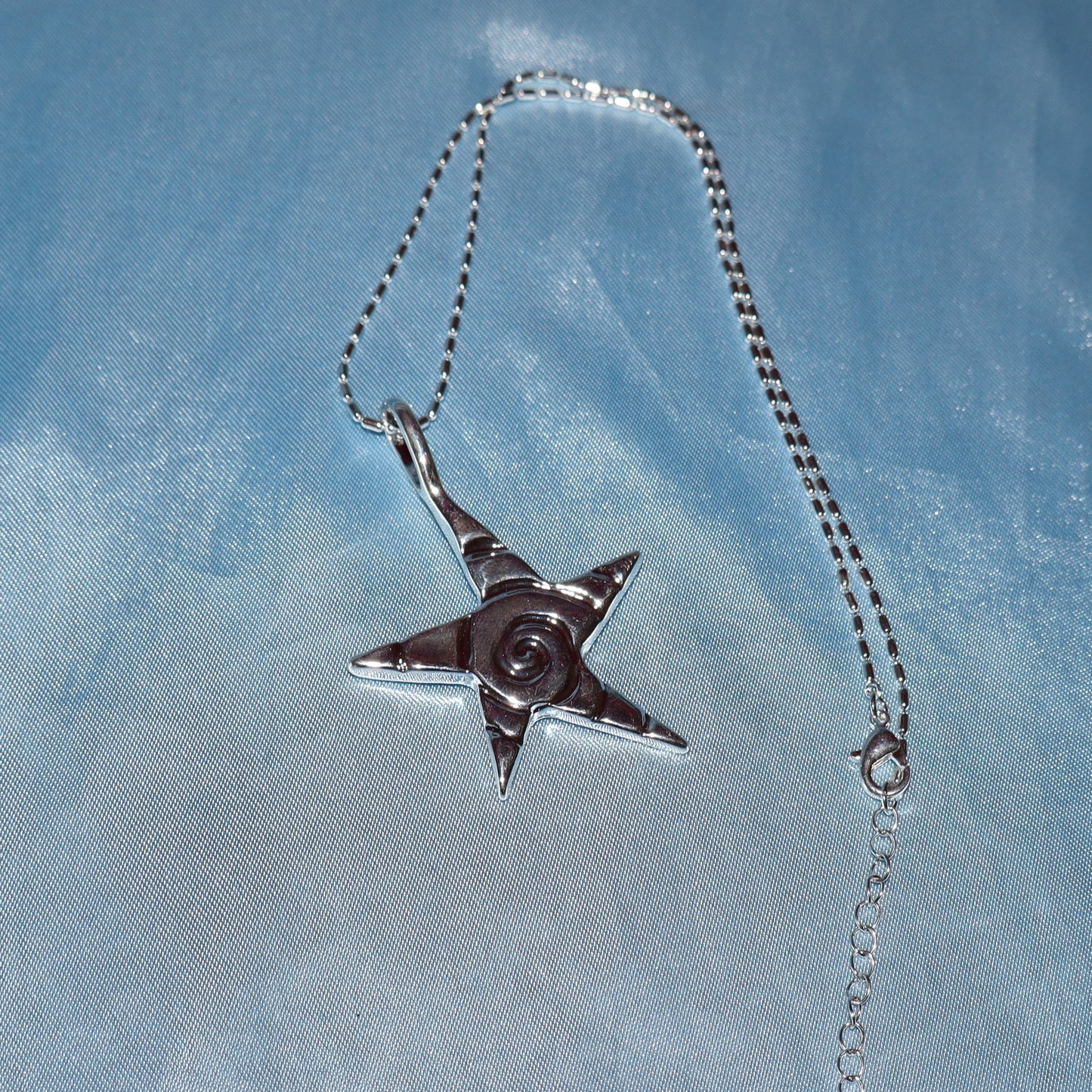 Star pendant, with a swirl design, silver chain necklace.