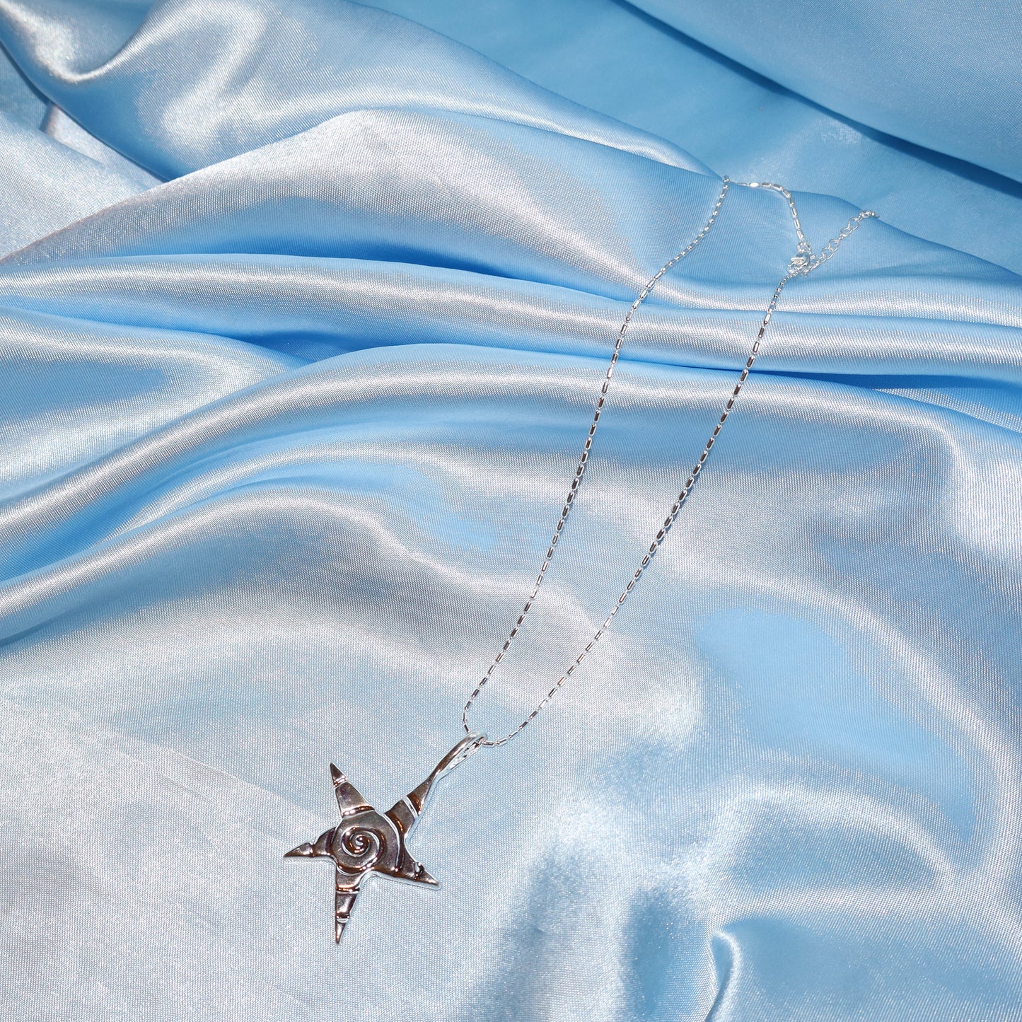 Star pendant, with a swirl design, silver chain necklace.