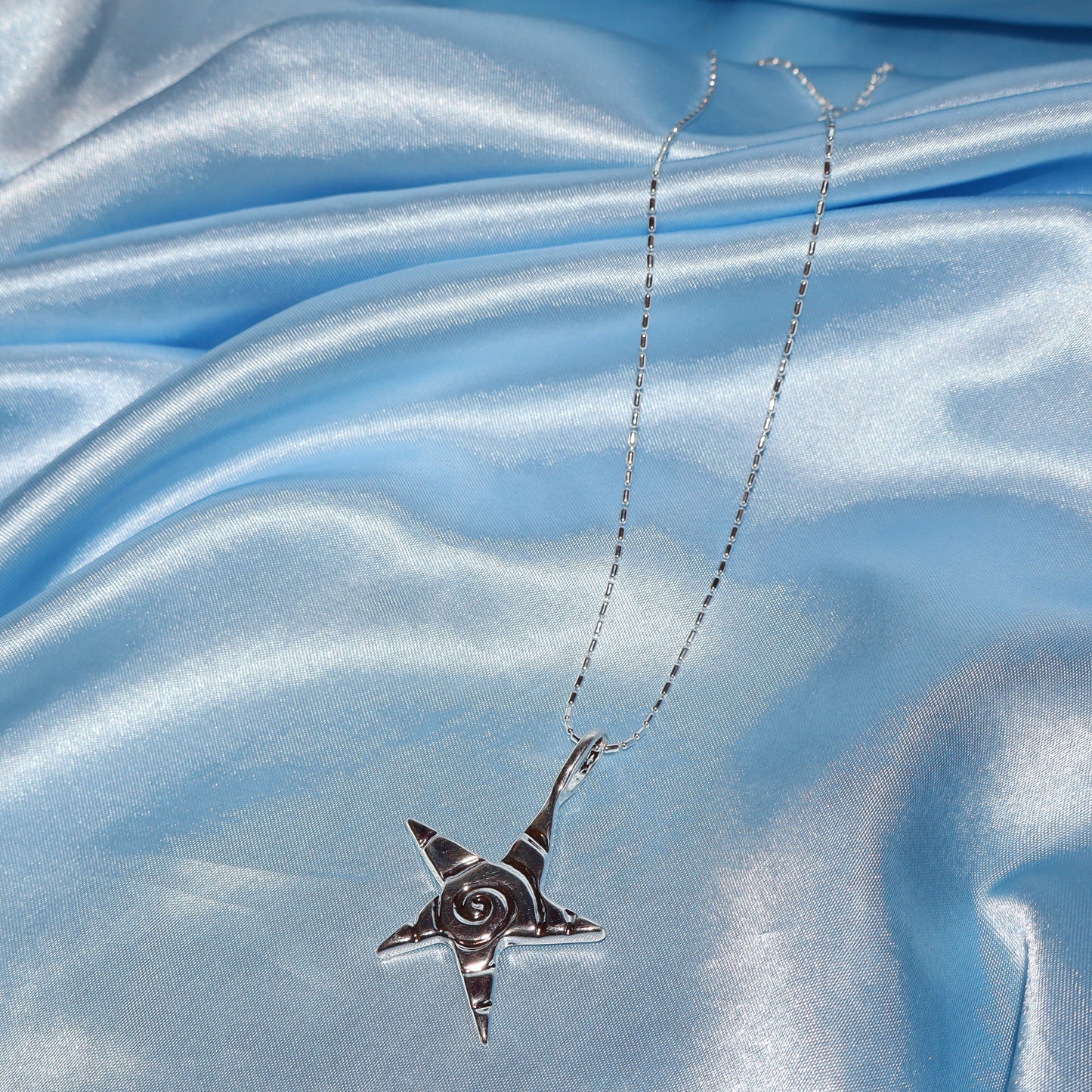 Star pendant, with a swirl design, silver chain necklace.
