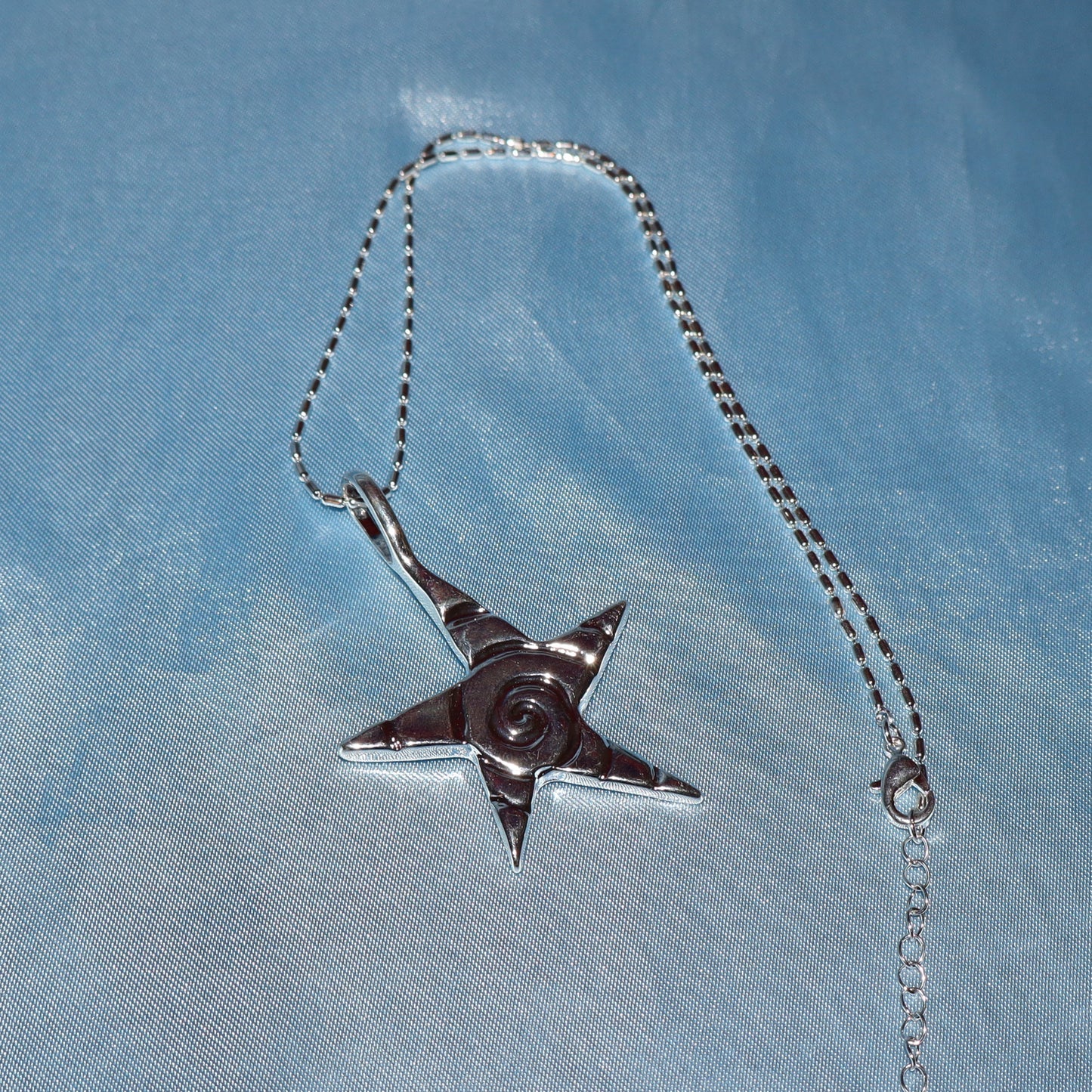 Star pendant, with a swirl design, silver chain necklace.
